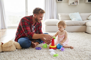 Young father and toddler daughter playing in sitting room