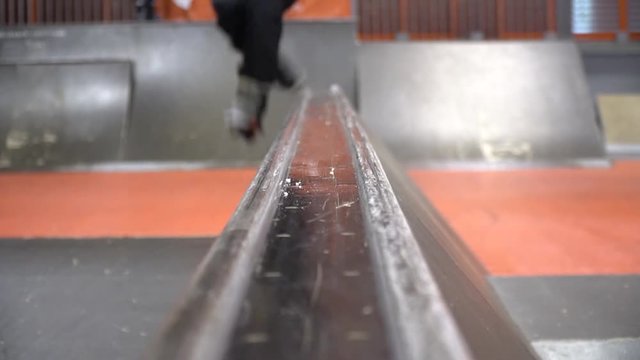 Front view as on the railing jumps the roller and performs Footy Grind, slow motion. Niffty