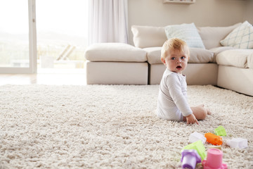 White toddler boy sitting on the floor in sitting room