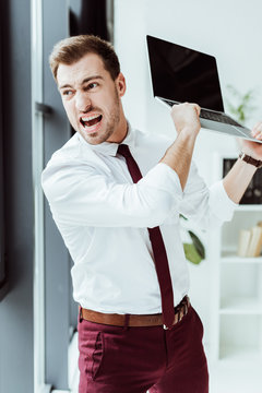 aggressive businessman yelling and throwing laptop in office