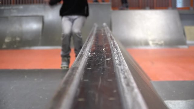 Front view as a man on rollers jumps on the railing and makes a trick a cheese grater, slow motion
