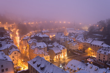 Grund, old town of Luxembourg city enveloped in early morning fog and covered in snow