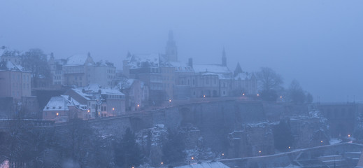 Luxembourg city enveloped in early morning fog and covered in snow
