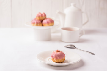 A homemade air dessert is profiterole with a delicate cream decorated with a pink frosting for breakfast.