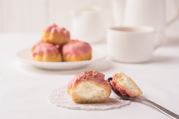 A homemade air dessert is profiterole with a delicate cream decorated with a pink frosting for breakfast.
