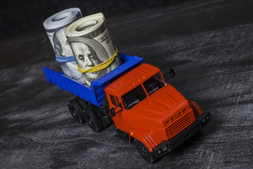 Naklejka premium Many bills in one hundred dollars on a toy plastic truck