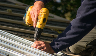 Man screwing in tin roofing