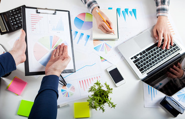 Business people discussing the charts and graphs showing the results of their successful teamwork.  Stock market chart and finger pointing on tablet in office.