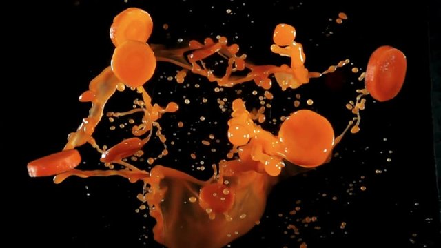 Fresh organic carrots with juise bouncing against to the camera on a black background in slow motion