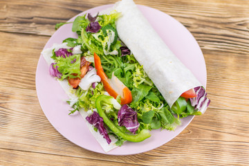 Fresh salad of greens in pita bread on a wooden background  for healthy lifestyle concept.