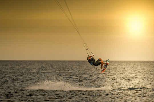 Kitesurfer jumping over the waves in Tenerife at the sunset. Kiter riding the waves on the ocean, enjoying the wind of a beautiful summer day.