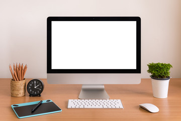 All in one computer, mouse, keyboard, touch tablet, pen, clock, pencils and plant vase  on wooden table