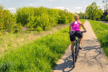 Naklejka premium Woman cycling a mountain bike in city park, summer day