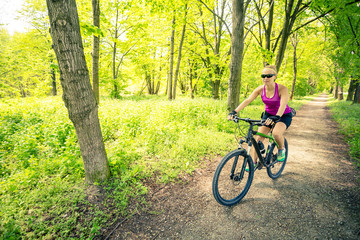 Obraz premium Woman cycling a mountain bike in city park, summer day
