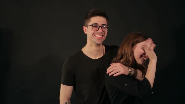 Portrait of happy beautiful couple of hipsters, a man licks the face of his girl on a black background.
