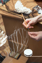 Женщина вышивает бисером по прозрачной ткани.