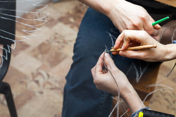 Женщина вышивает бисером по прозрачной ткани.