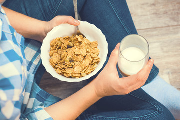 The girl is holding a plate of cereal with fruit and milk. Healthy eating concept. Proper nutrition. Healthy food. Toned image.
