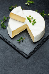 Camembert cheese and cut a slice on stone serving board