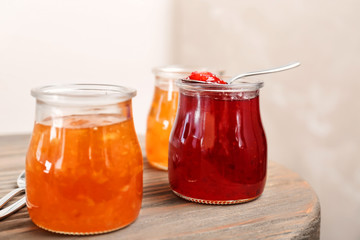 Fototapeta na wymiar Jars with tasty sweet jam on wooden table