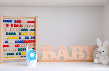 Baby monitor, toys and wooden letters on shelf