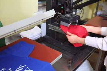 Young woman printing on cap at workshop