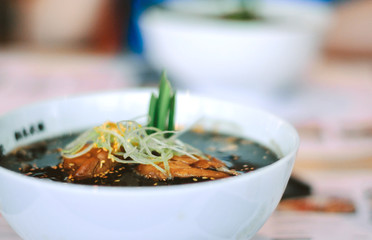 Soup in a white plate, background in blur. Close-up