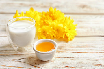Glass of milk and bowl with honey on wooden background