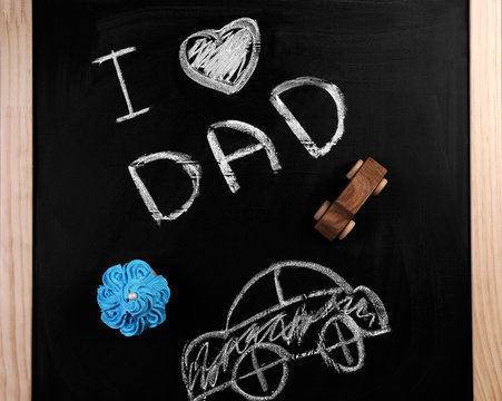 Phrase "I love dad", cupcake and car on chalkboard. Father's day celebration