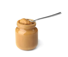 Jar and spoon with creamy peanut butter on white background