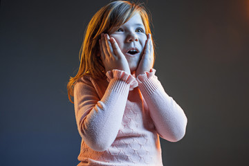 The young attractive teen girl looking suprised isolated on dark blue