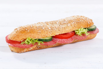 Sandwich whole grain grains baguette with salami ham on wooden board