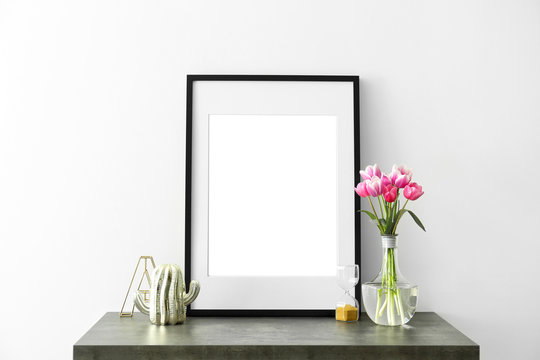 Mockup of blank frame and flowers on table