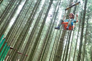 Fototapeta premium boy at climbing activity in high wire forest park