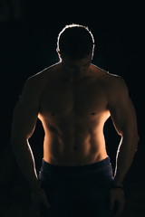 Fototapeta premium Silhouette of a strong man with dramatic light and dark background