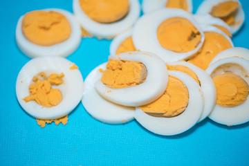 Hard boiled eggs cut up on a blue cutting board