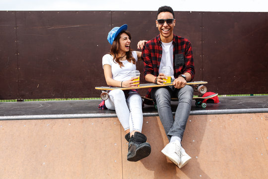 Young teen couple sitting on ramp and hangout at the skate park .Laughing and fun.