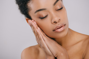 sensual african american woman with perfect skin leaning head on hands isolated on grey