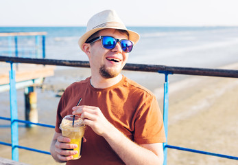 lifestyle, drinks and people concept - man in sunglasses drinking coffee frappe from disposable...