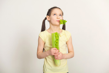 Thoughtful little girl eating celery leaves