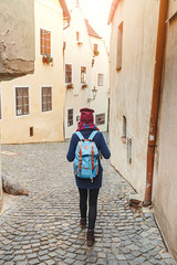 Obraz na płótnie Canvas Woman tourist in a coat with a backpack travels at the old streets of Cesky Krumlov city, Europe vacation concept