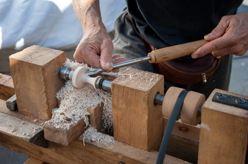 An artisan carves a piece of wood using a manual lathe