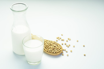 Soy milk in glass and soy beans on white background.