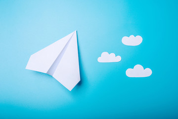 White paper origami airplane lies on pastel blue background