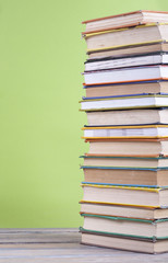 Book stacking. Open hardback books on wooden table and green background. Back to school. Copy space for ad text