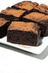 dessert - pieces of chocolate brownies on white table, vertical