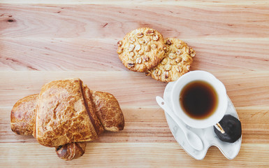 Breakfast. Cup of tea and two cookies, croissant on the wood table. Top view