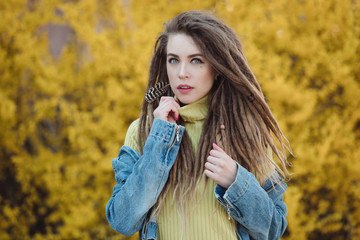 Portrait of woman with dreadlocks against yellow shrub background