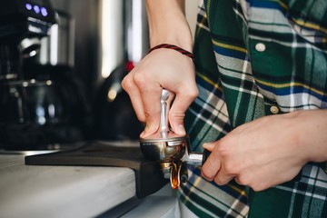 Male Barista in a green shirt, ground coffee beans closeup