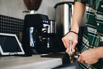 Male Barista grind the coffee beans closeup